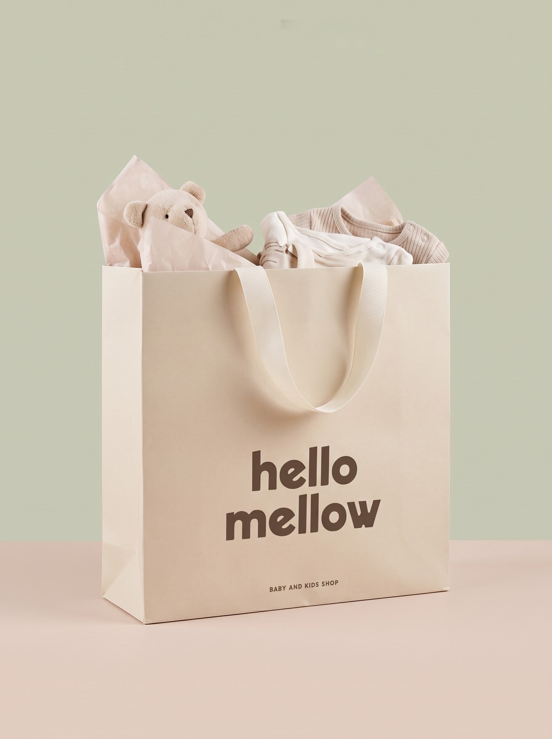 Bolsa de regalo Hello Mellow con peluche y ropa de bebé envueltos en papel de seda